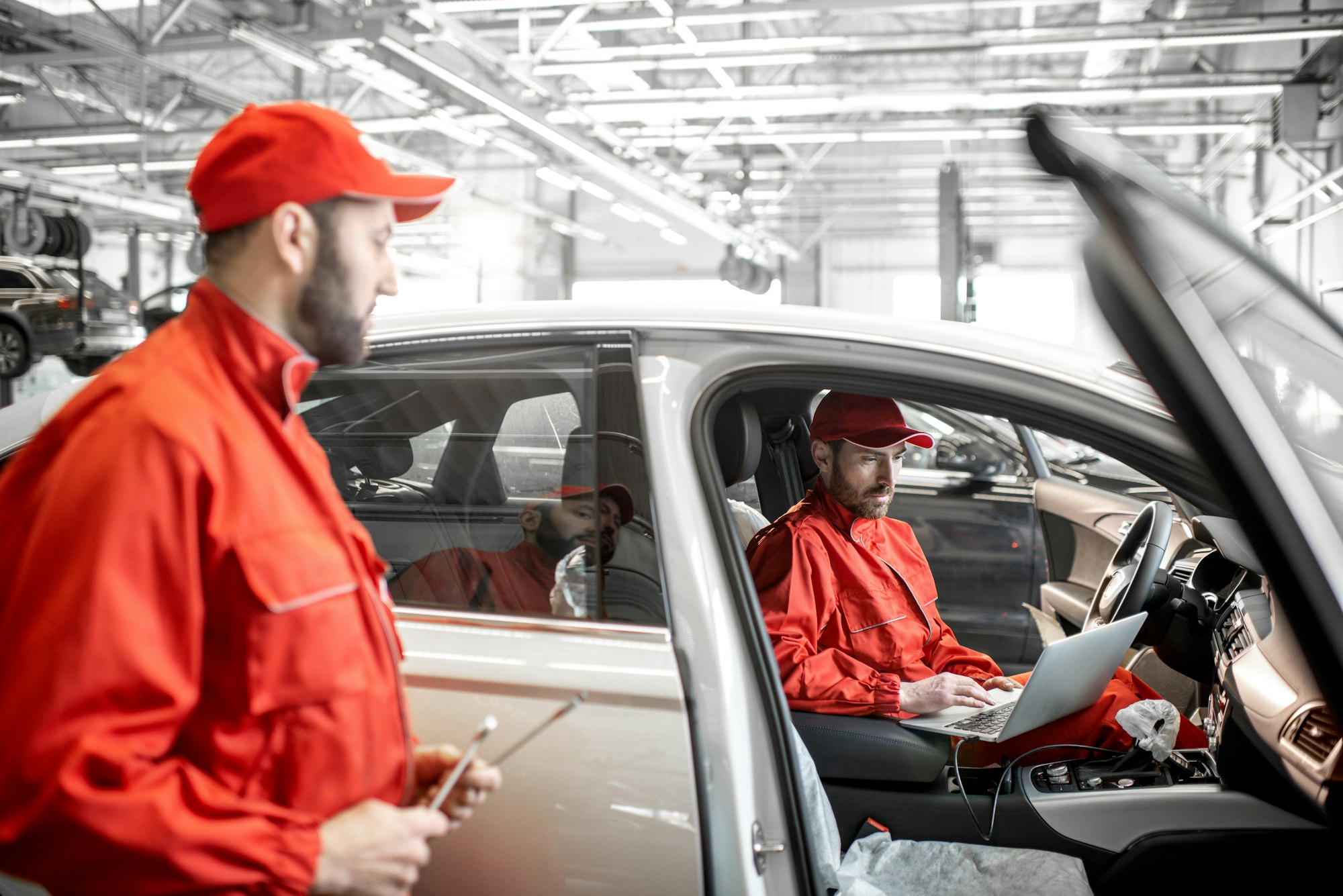 Auto mechanics diagnosing car with computer