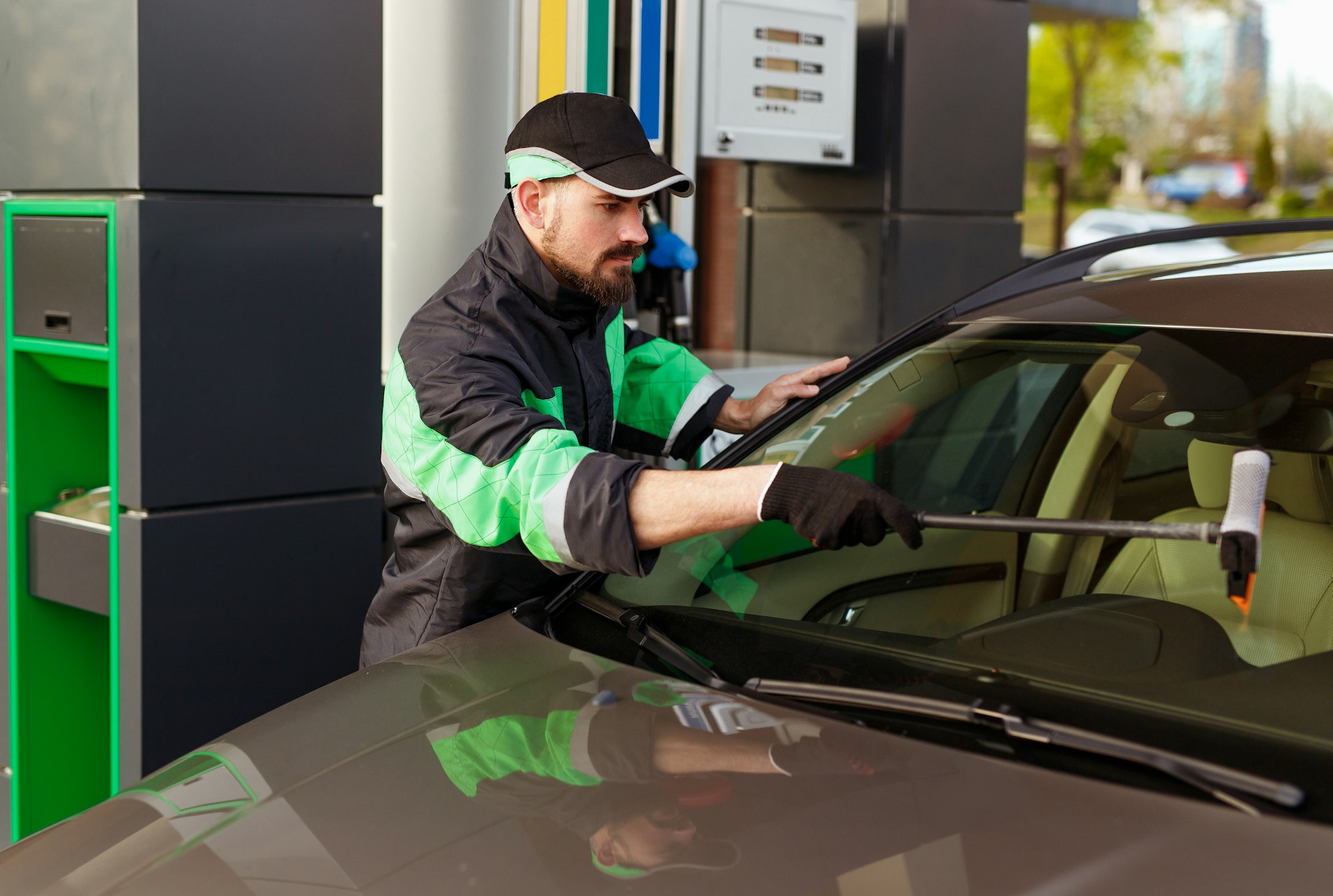 Petrol station employee washing windshield